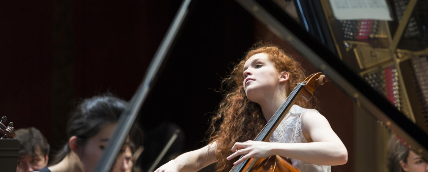 A cellist plays among an orchestra